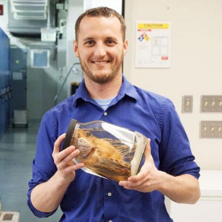 A male researcher holds a jar with a fish inside