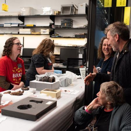 staff talk with visitors through an open door with artifacts on the table between then