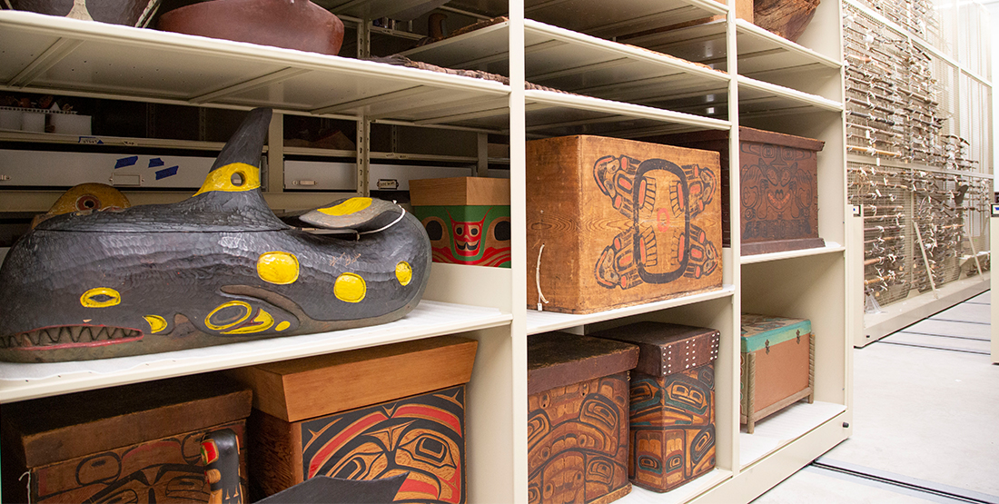 a compactor filled with bentwood boxes and large wooden carvings