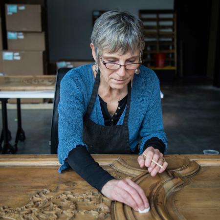 A woman gently cleans the boiserie panel with a cotton ball