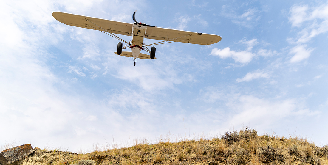 An airplane flies over a hill side