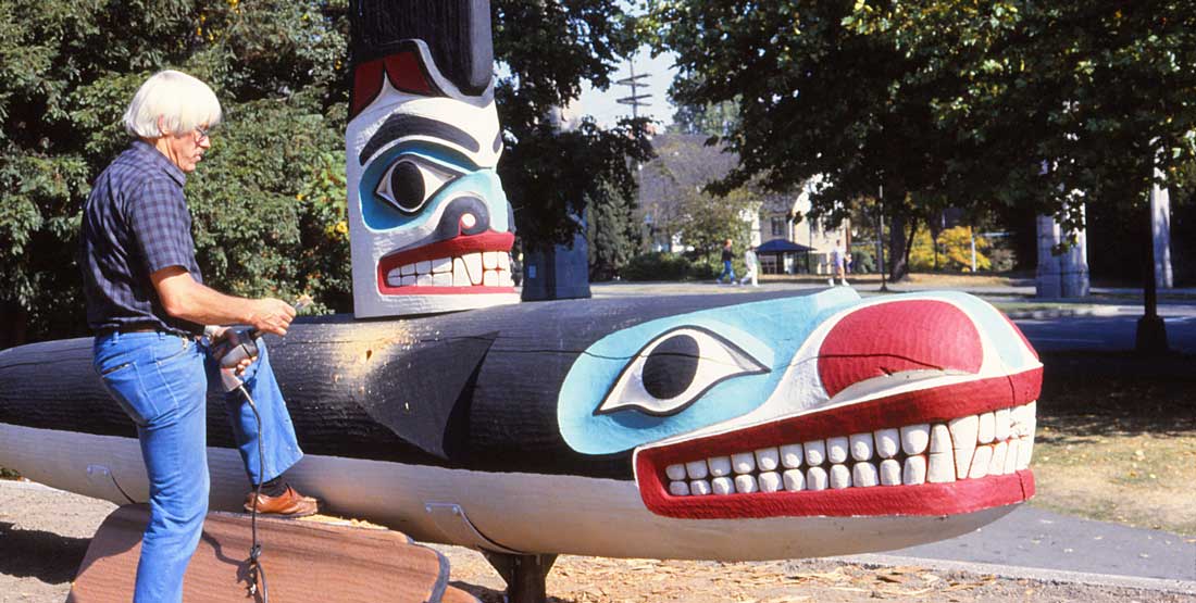 bill holm stands outside the burke and assembles a wood whale carving