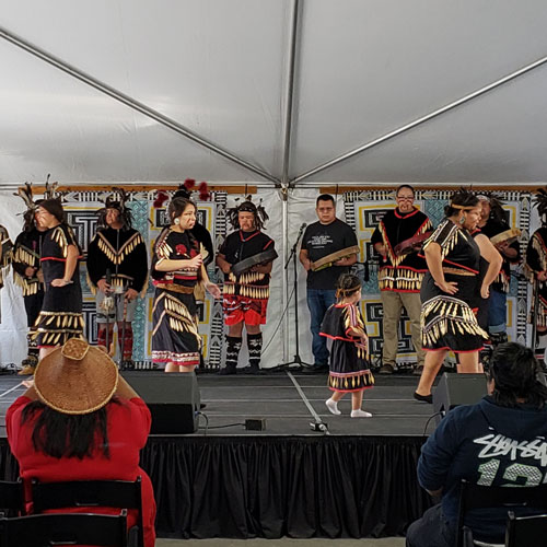 lummi dance group on stage in regalia