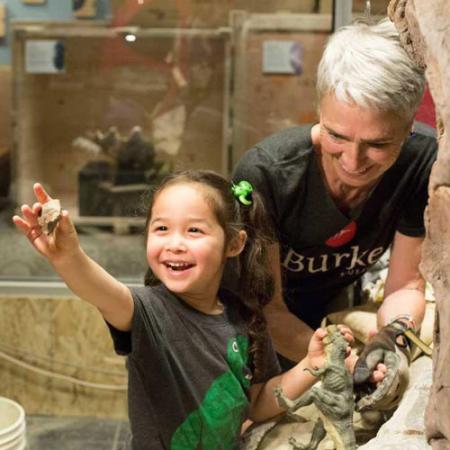 A young girl extending her arm to show her mom a piece of rock she found