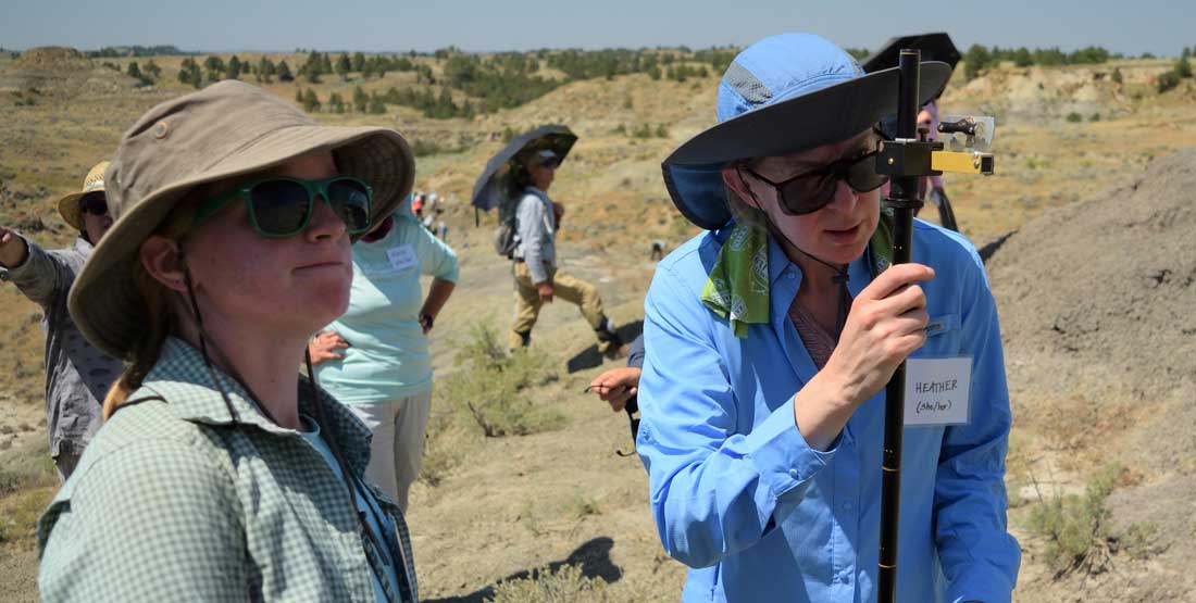 DIG Instructor, Paige Wilson Deibel, stands by while a participant measures the stratigraphic layer using a Jacob staff.