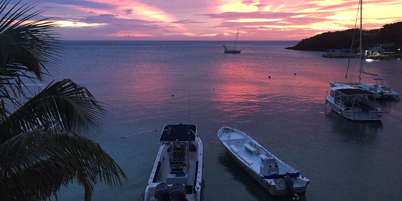 sunset on the water with boats anchored offshore