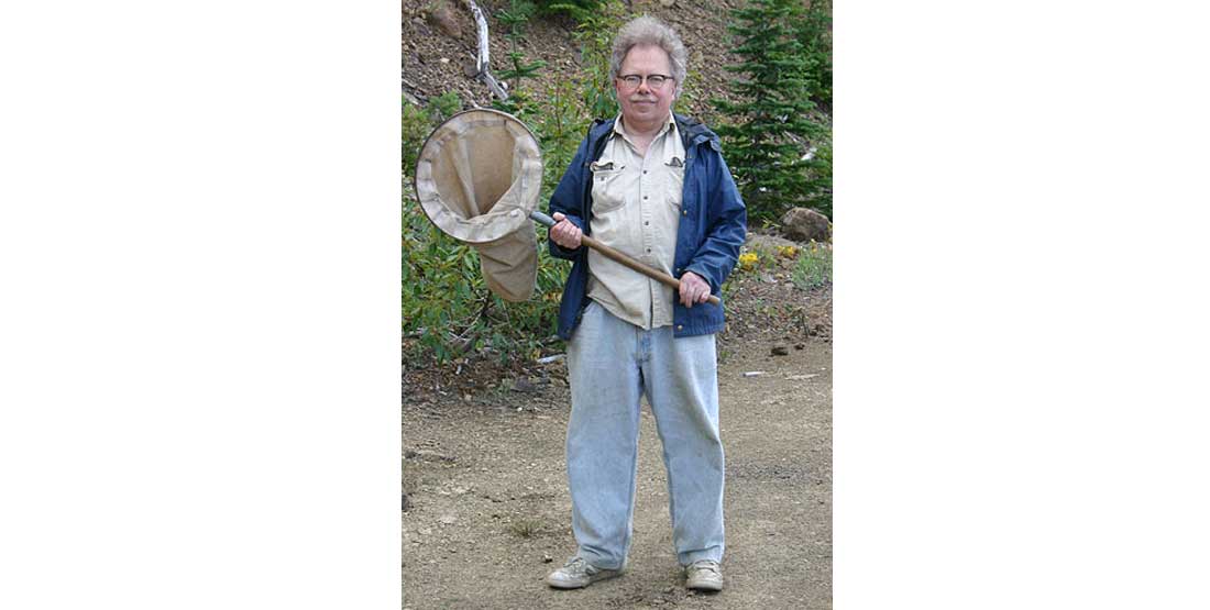 Rod Crawford stands holding a large insect net