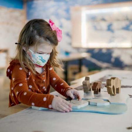 a kid plays with a wooden ice age puzzle
