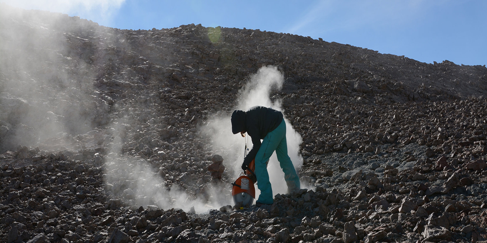 Dust fills the sky as a young woman uses a rock saw