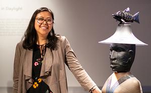 portrait of miranda belarde-lewis standing next to a scultpture by preston singletary